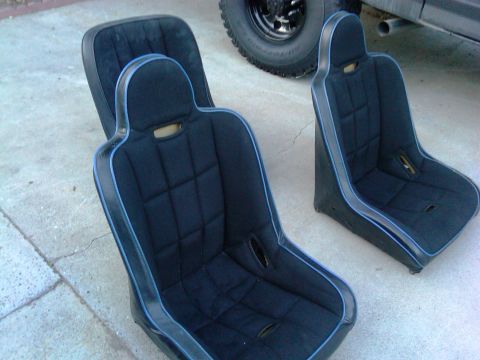 1986 Ford Bronco - Pair of aftermarket bucket seats with blue trim. Background shows a tire and exhaust.
