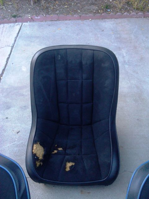 1986 Ford Bronco - A worn car seat is shown outdoors on a concrete surface, with visible damage to the upholstery.