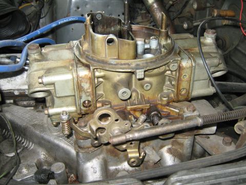 1985 Ford Mustang - Close-up view of a carburetor, with a blue "Ford Racing" hose visible in the background.