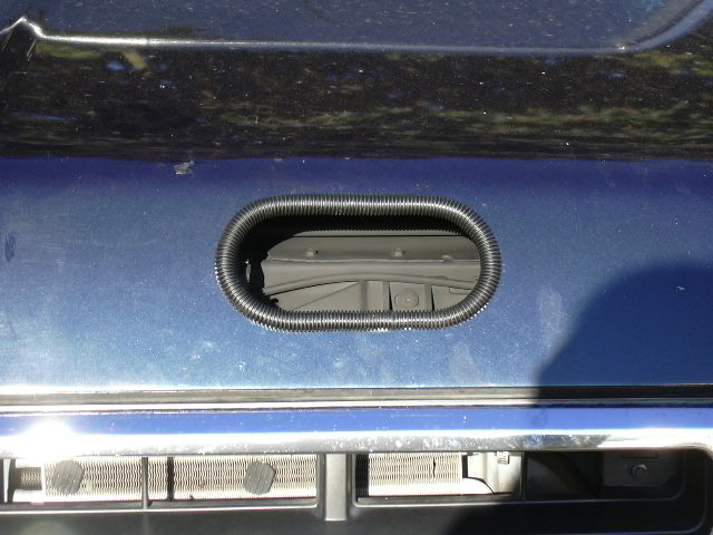 Oval opening with black trim in dark blue body panel above chrome bumper