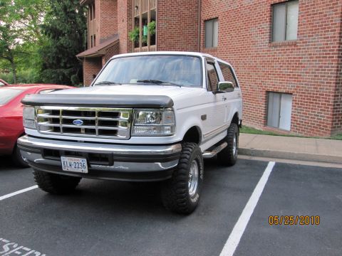 1996 Ford Bronco - This 1996 Ford Bronco is captured in a front three-quarter view, parked in a lot with a brick building in the background.