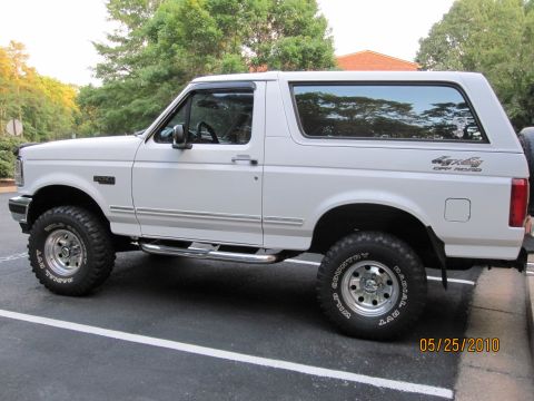 1996 Ford Bronco - Side view of a white 1996 Ford Bronco with off-road tires and chrome side steps.