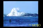 1991 Ford Bronco - A powerful wave crashes against a rocky shore under a clear blue sky.