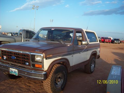 1985 Ford Bronco - This 1985 Ford Bronco features a two-tone brown and white paint scheme and a prominent front grille.