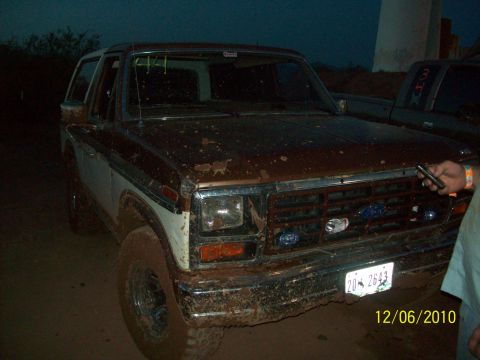 1985 Ford Bronco - A muddy Ford Bronco is parked outdoors, with another vehicle visible in the background.