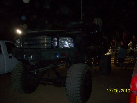 1985 Ford Bronco - A black lifted truck is parked outdoors at night with people in the background.