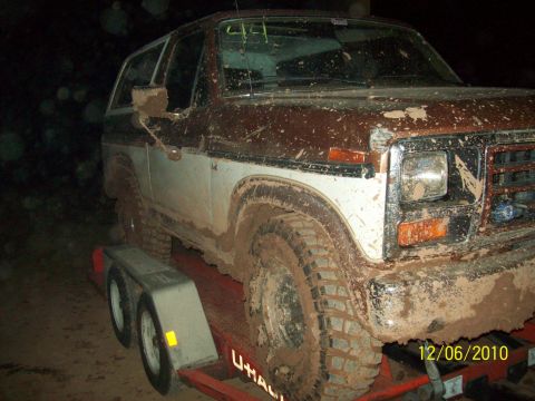 1985 Ford Bronco - This muddy Ford Bronco is loaded onto a trailer, likely after off-roading.