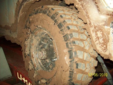 1985 Ford Bronco - This vehicle's tire and fender are heavily covered in mud, suggesting recent off-road activity.