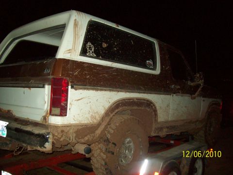 1985 Ford Bronco - This 1985 Ford Bronco is heavily covered in mud, seen from the rear quarter angle.