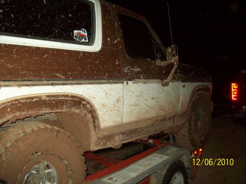 1985 Ford Bronco - This 1985 Ford Bronco is heavily covered in mud, seen from the side at night.