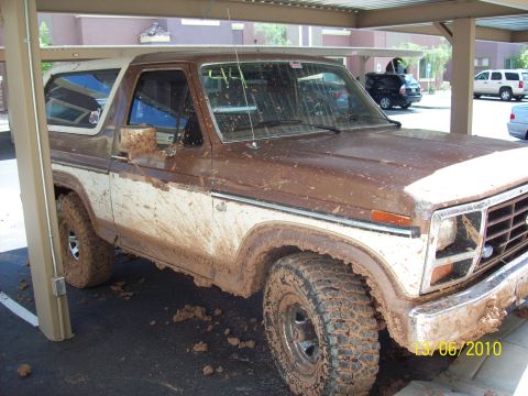 1985 Ford Bronco - This heavily mud-caked Ford Bronco is parked under a carport, showing off its off-road adventures.