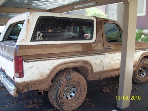 1985 Ford Bronco - This 1985 Ford Bronco is heavily covered in mud, suggesting recent off-road use.