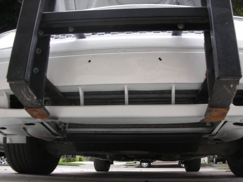 2004 Ford Crown Victoria - The underside of a white vehicle shows black push bumper brackets attached to the front end.