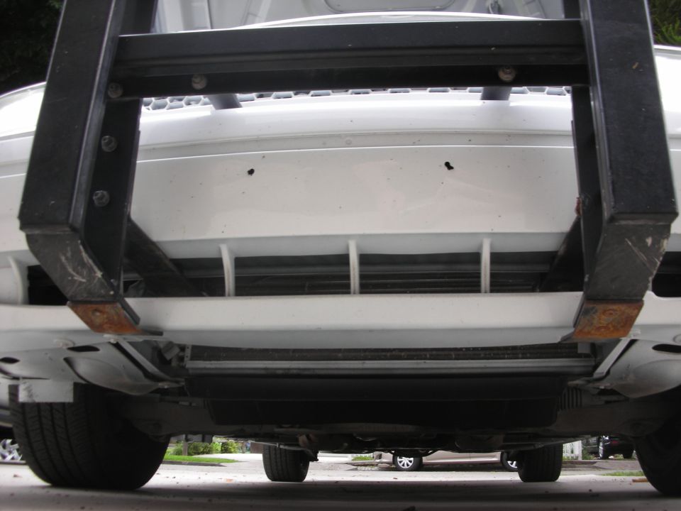 Push bumper bracketry on a white vehicle's front end, viewed from below