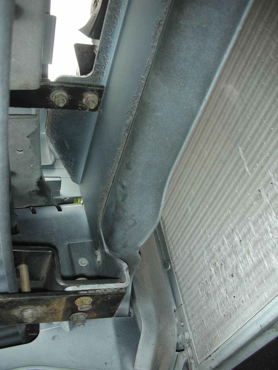 Close-up of a vehicle's radiator and its metal mounting bracketry