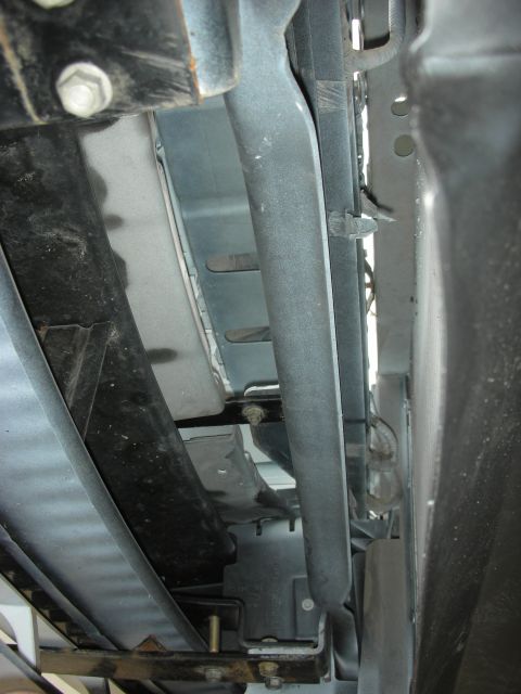 2004 Ford Crown Victoria - A close-up view of the undercarriage reveals various structural and mechanical components, including brackets and wiring harnesses.
