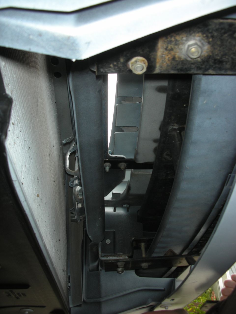 Radiator core, fan shroud and rusty radiator support brackets with front bodywork removed