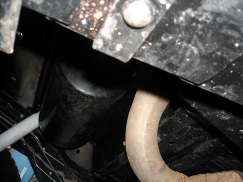 1985 Ford Bronco - Close-up shot of the undercarriage of a vehicle, showing the exhaust system and a large black tank.
