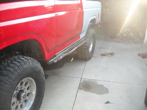 1985 Ford Bronco - A partially painted Ford Bronco sits in a garage with large off-road tires.