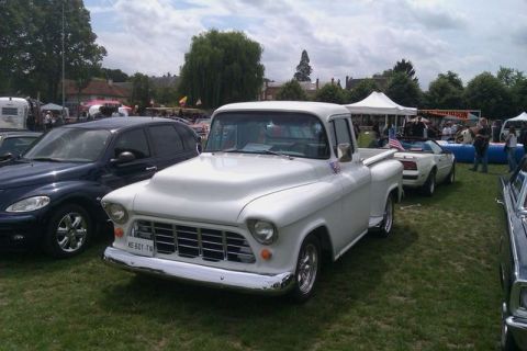 1991 Ford Crown Victoria - A classic white pickup truck is displayed at an outdoor event with other vehicles and tents visible.