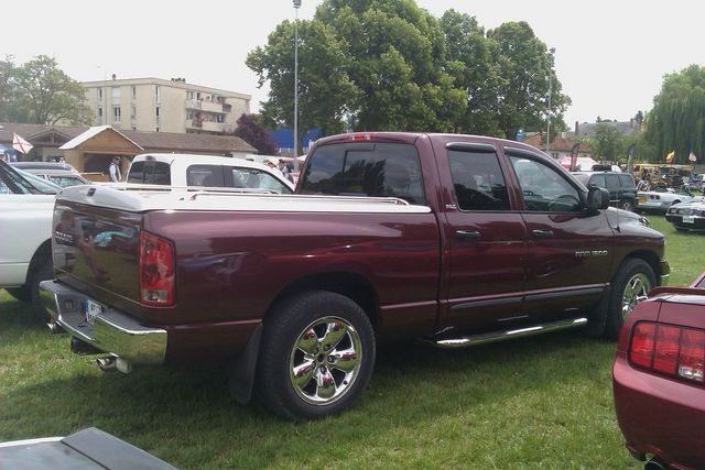Maroon Dodge Ram pickup truck, rear 3/4 view, parked on grass
