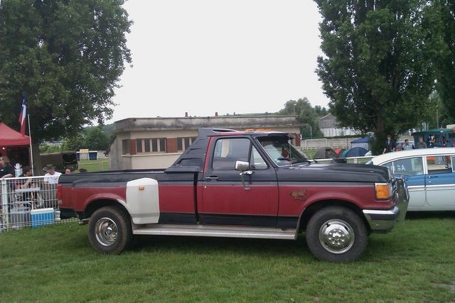 Two-tone red and black Ford F-Series truck with a dually rear end and a cab extender