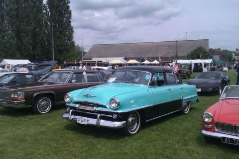 1991 Ford Crown Victoria - A 1954 Plymouth Belvedere sedan is parked on grass at an outdoor event with other cars.