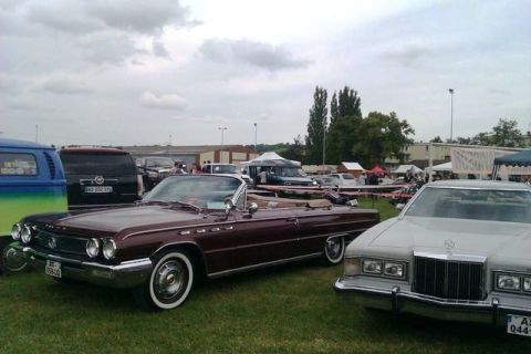 1991 Ford Crown Victoria - A maroon convertible is parked on a grassy field with other vehicles and tents in the background.