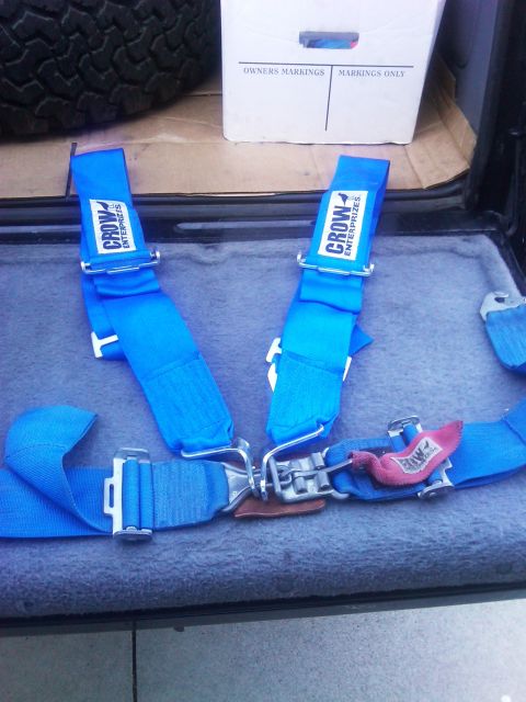1986 Ford Bronco - Blue racing harnesses from Crow Enterprises are visible, along with a spare tire and a box in the background.