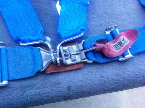 1986 Ford Bronco - Close-up of a blue racing harness buckle, a pink tag with 'ROW NEIPRIZES' text.