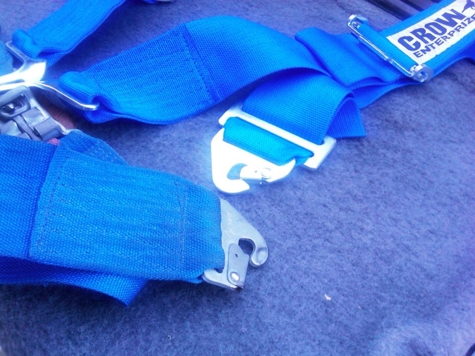 Blue racing harness with a "CROW ENTERPRIZE" label and metal buckle