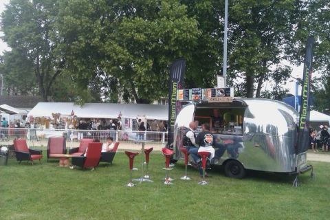 1991 Ford Crown Victoria - A food truck with seating area and tents in the background at an outdoor event.
