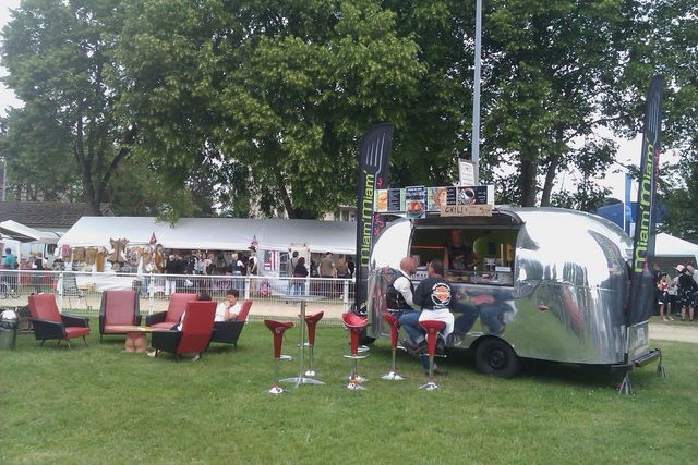 Silver Airstream-style food truck with Miami Miami branding, parked on grass with seating area