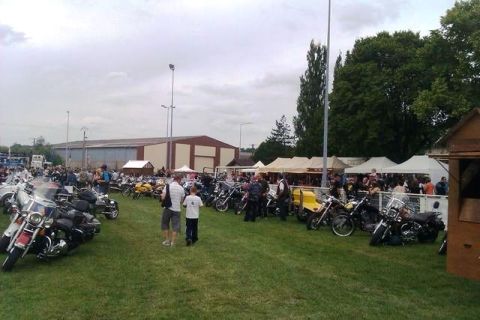 1991 Ford Crown Victoria - A large gathering of motorcycles parked on a grassy field, with tents and people milling about in the background.