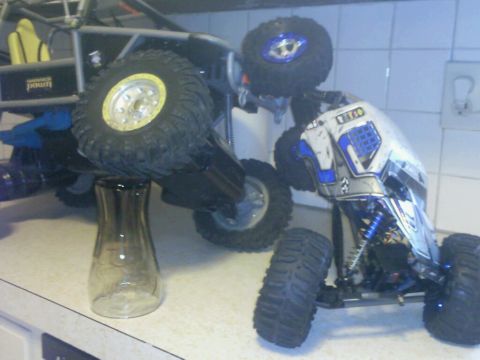 1996 Ford Bronco - Two remote control rock crawlers are positioned on a countertop, with one elevated by a glass vase.
