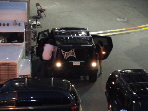 1996 Ford Bronco - A black SUV with a large 'Tapout' logo on its rear is parked next to a white semi-truck.