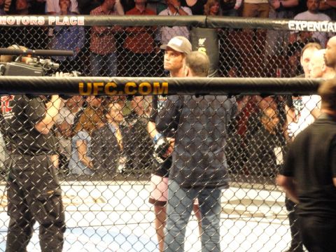 1996 Ford Bronco - Fighters stand in the UFC octagon, with a camera operator and spectators in the background.
