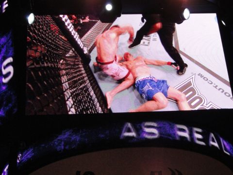 1996 Ford Bronco - A mixed martial arts match is underway inside a cage with a referee present.