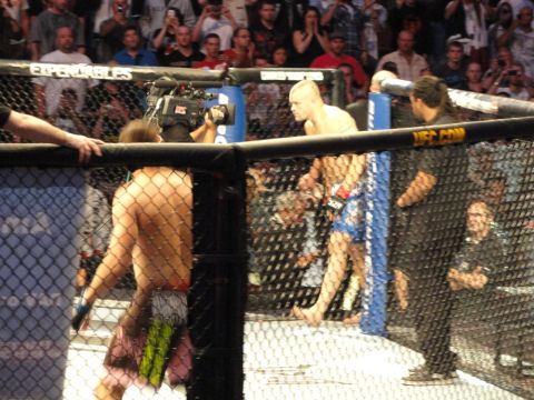 1996 Ford Bronco - A mixed martial arts match is underway inside a cage, with spectators watching.