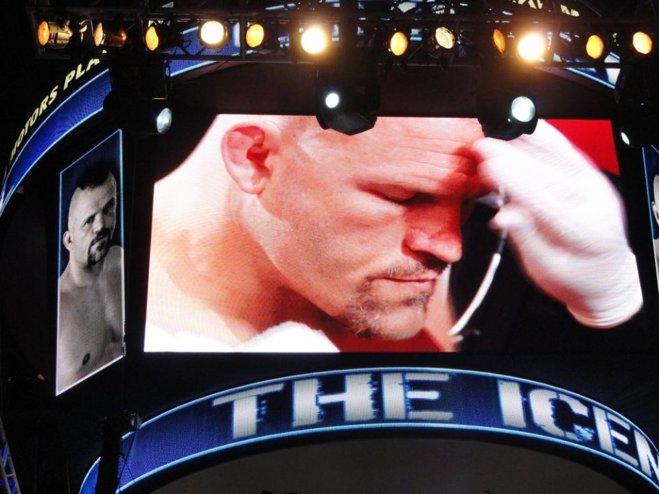 Close-up of a fighter's face on a large screen, with a smaller image of another fighter to the left