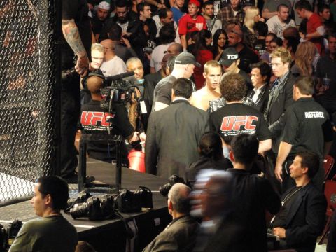 1996 Ford Bronco - A crowd watches as UFC fighters are prepared for a match, with camera operators and officials nearby.