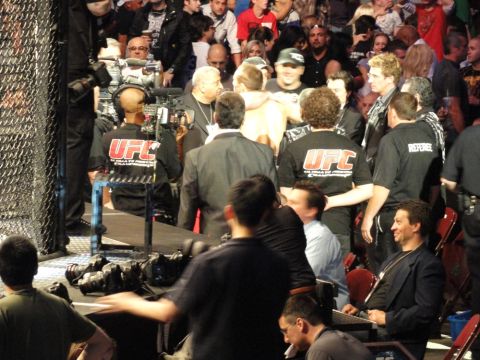 1996 Ford Bronco - A crowd watches a UFC event, with several officials and attendees visible in the foreground and background.