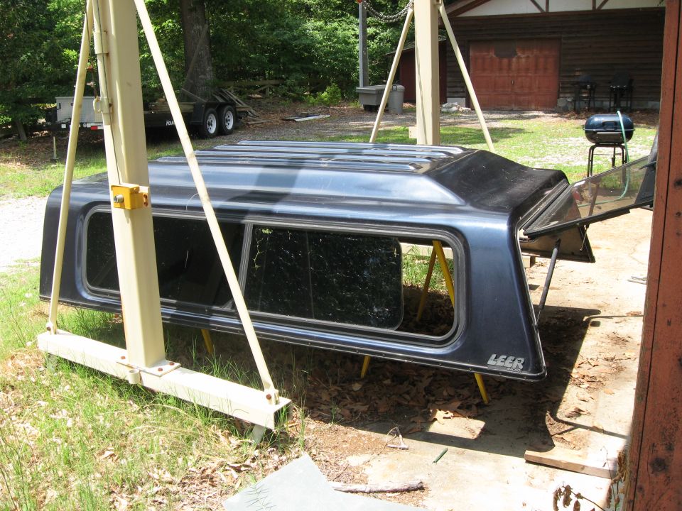Dark blue LEER truck cap on sawhorses in a yard with rear hatch open