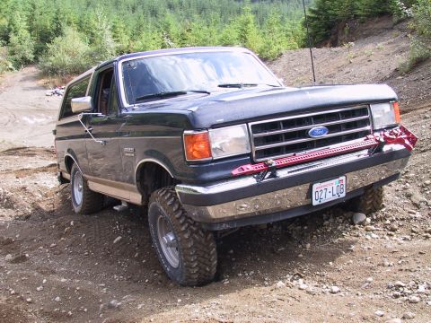 1991 Ford Bronco - 1991 Ford Bronco navigating rough terrain, equipped with a Hi-Lift jack on the front bumper.