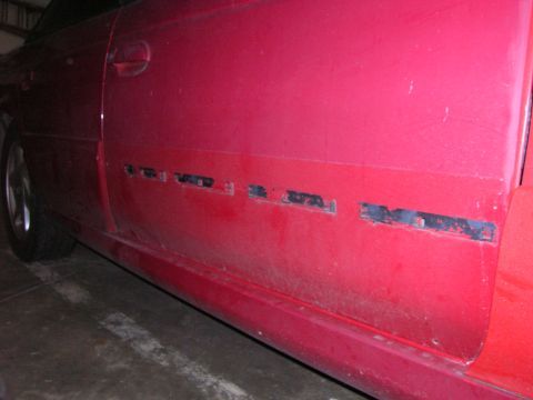 1993 Ford Taurus - Side view of a red car door showing damage and cutouts along the lower body panel.