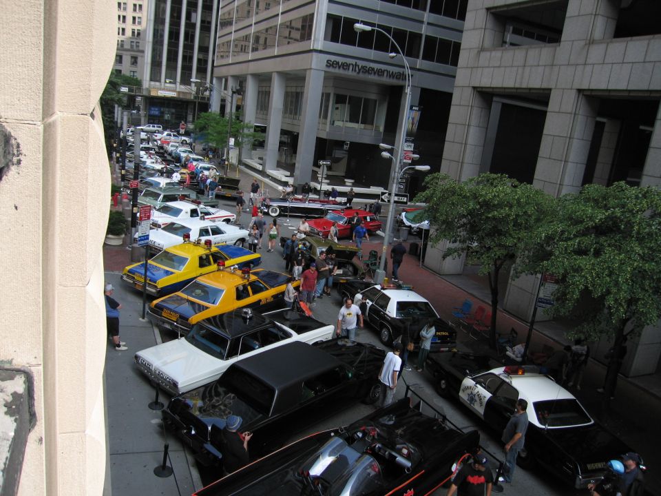Overhead view of a crowded city street car show with taxis and police cars