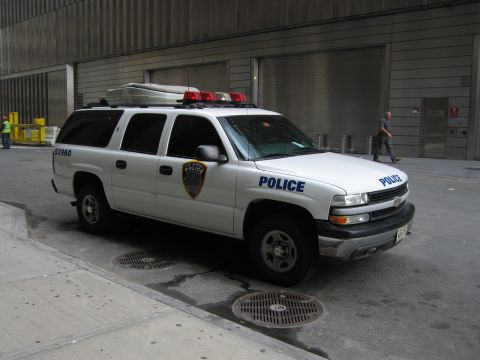 1991 Ford LTD Crown Victoria - white Chevrolet Suburban SUV lettered POLICE and numbered 53960, with a roof rack and light bar, is parked along a curb.