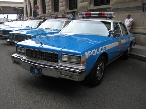 1991 Ford LTD Crown Victoria - blue-and-white NYPD POLICE sedan with red roof dome lights and plate 1270 is parked at the head of a row of matching cruisers.