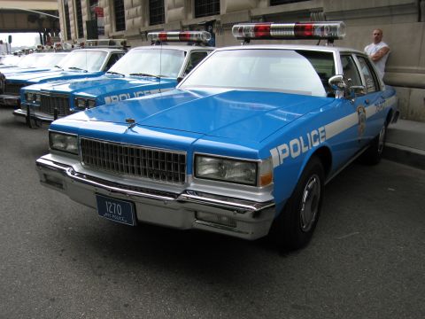 1991 Ford LTD Crown Victoria - blue-and-white NYPD POLICE sedan marked with plate 1270 and a red roof light bar is parked among other vintage cruisers.