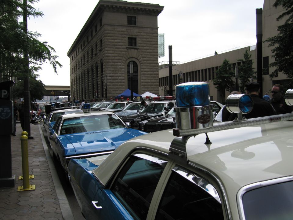 Row of vintage police cars lined along a city street by a stone building